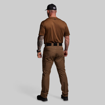 Man wearing a brown tactical outfit with a cap on a gray background