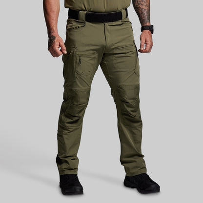 Person wearing olive green tactical pants on a gray background