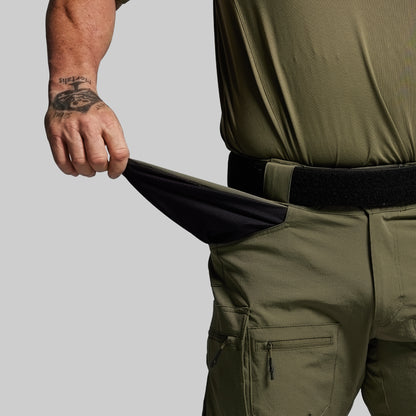 Person wearing olive green pants with a black belt on a gray background