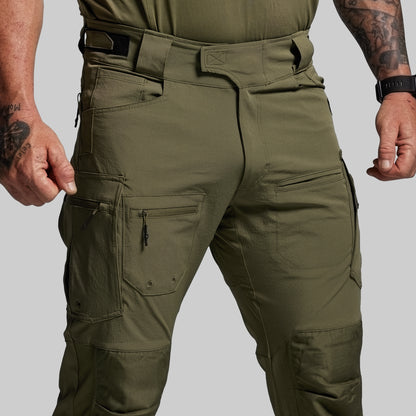 Olive green tactical pants with multiple pockets on a gray background