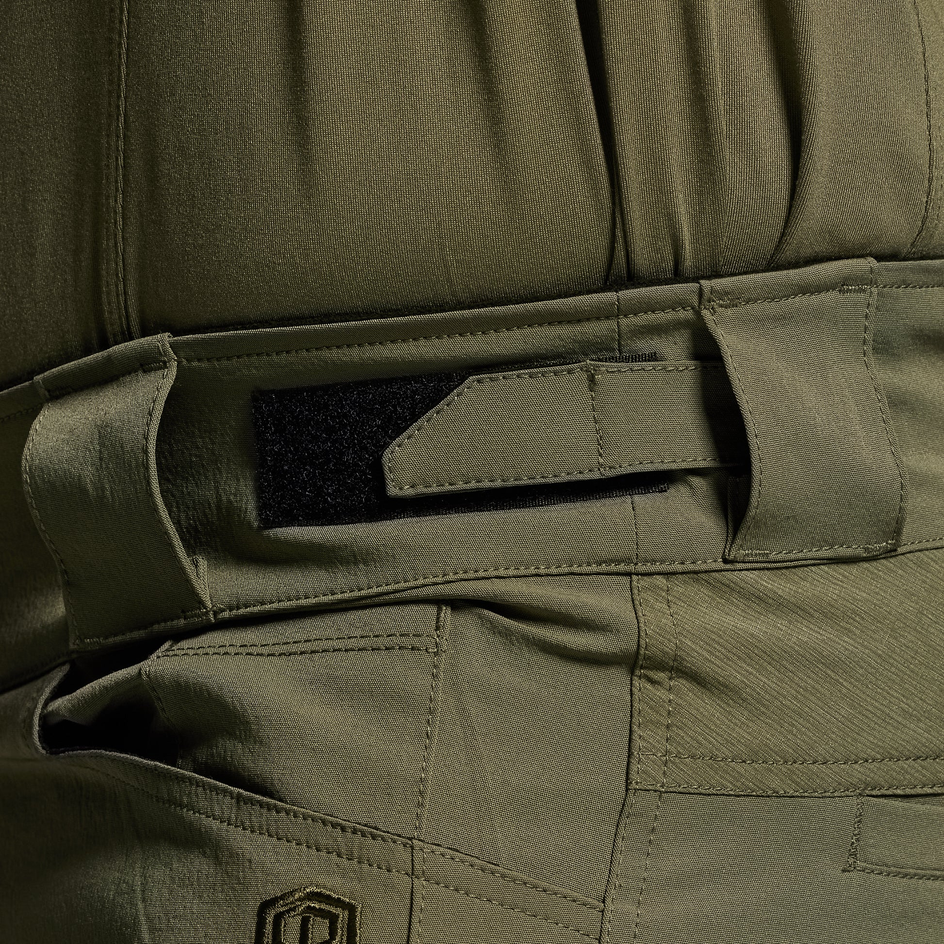 Close-up of green tactical pants with a focus on the adjustable waistband.