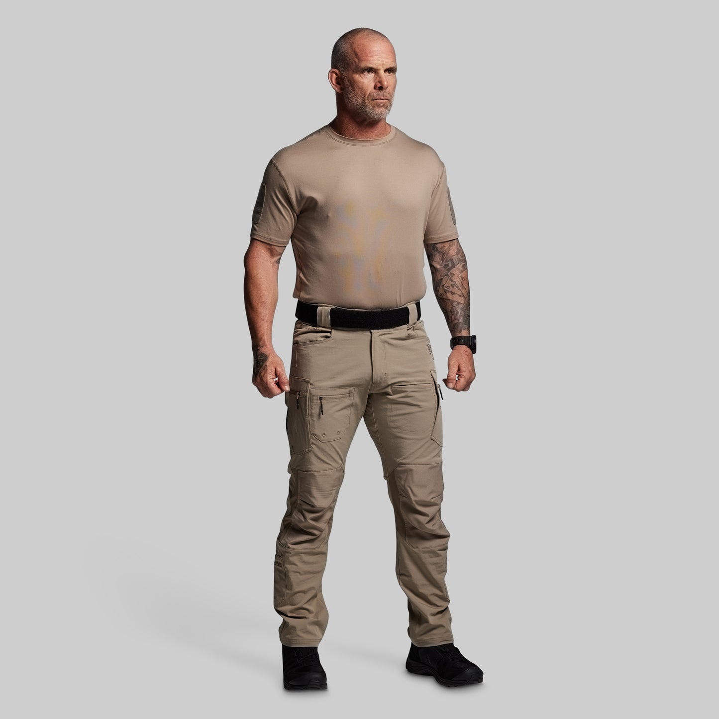 Man wearing a beige t-shirt and pants on a gray background