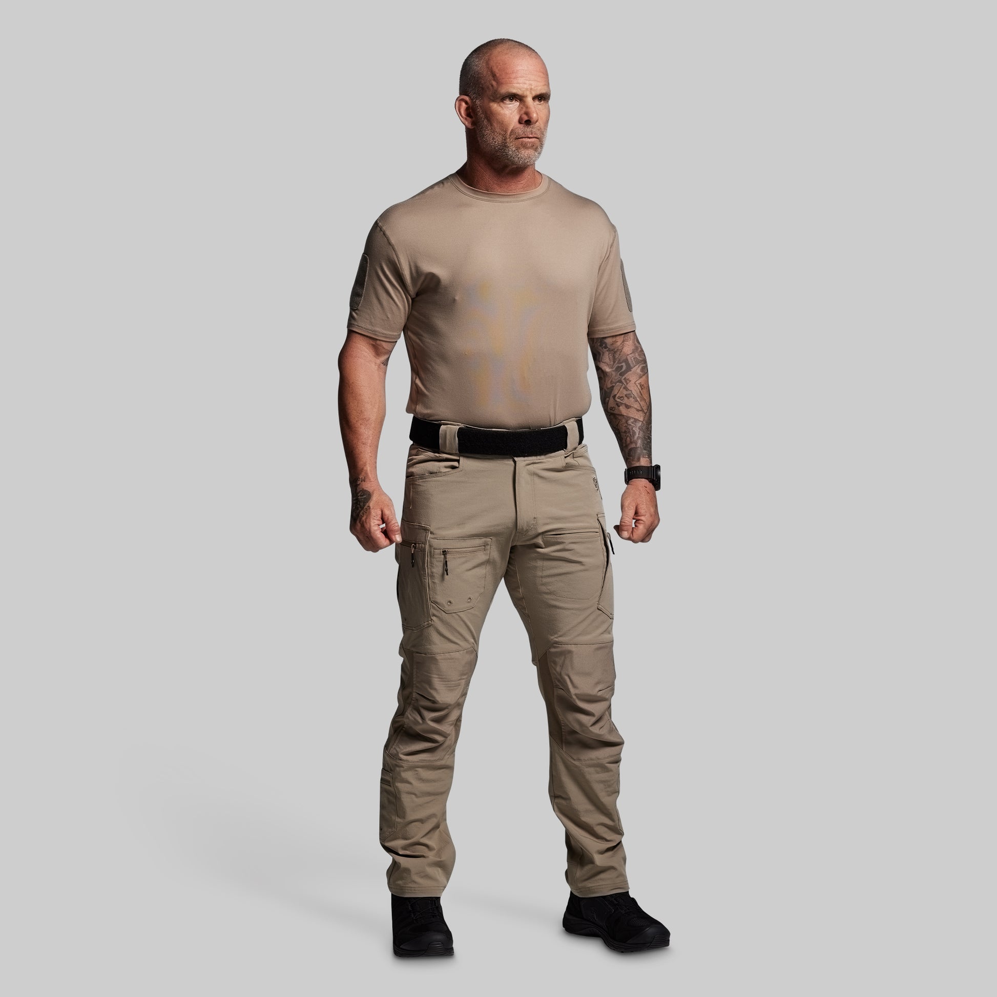 Man wearing a beige t-shirt and pants on a gray background