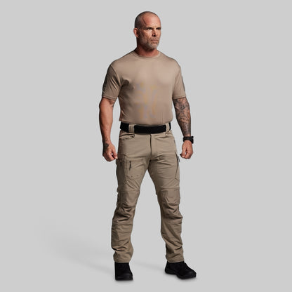 Man wearing a beige t-shirt and pants on a gray background