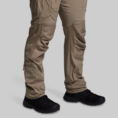 Beige tactical pants with black shoes on a light gray background
