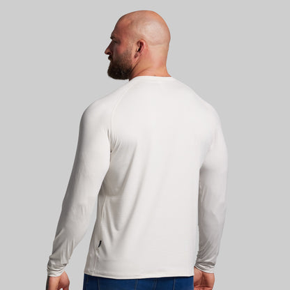 Man wearing a white long-sleeve shirt against a gray background