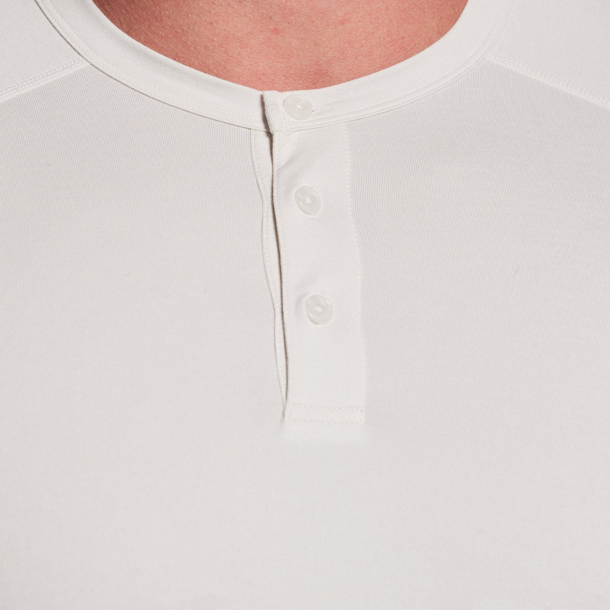 Close-up of a white shirt with button details on a light gray background