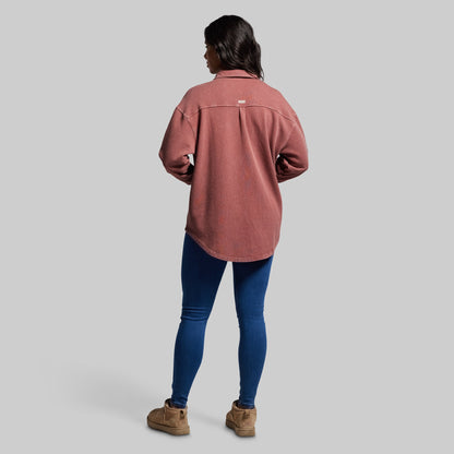 Person wearing a pink shirt and blue jeans on a gray background