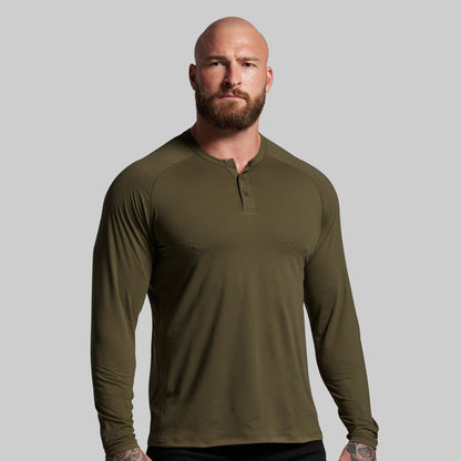 Man wearing an olive green long-sleeve shirt against a gray background