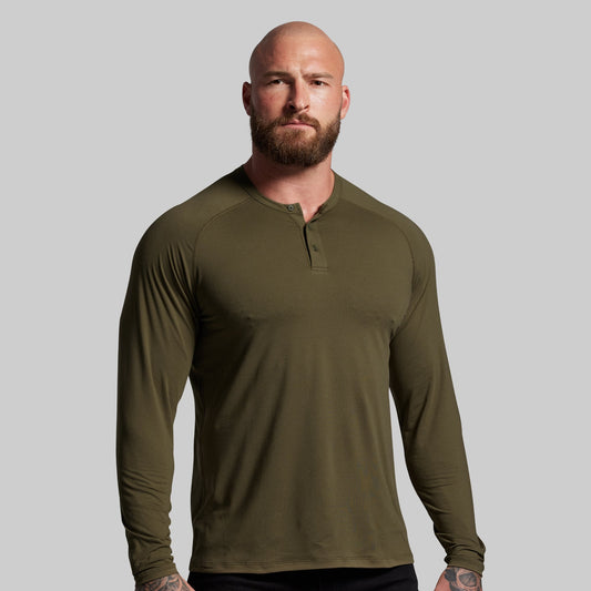 Man wearing an olive green long-sleeve shirt against a gray background