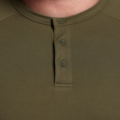 Close-up of a green henley shirt with buttons on a plain background