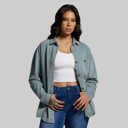 Woman wearing a denim shirt and blue jeans on a gray background