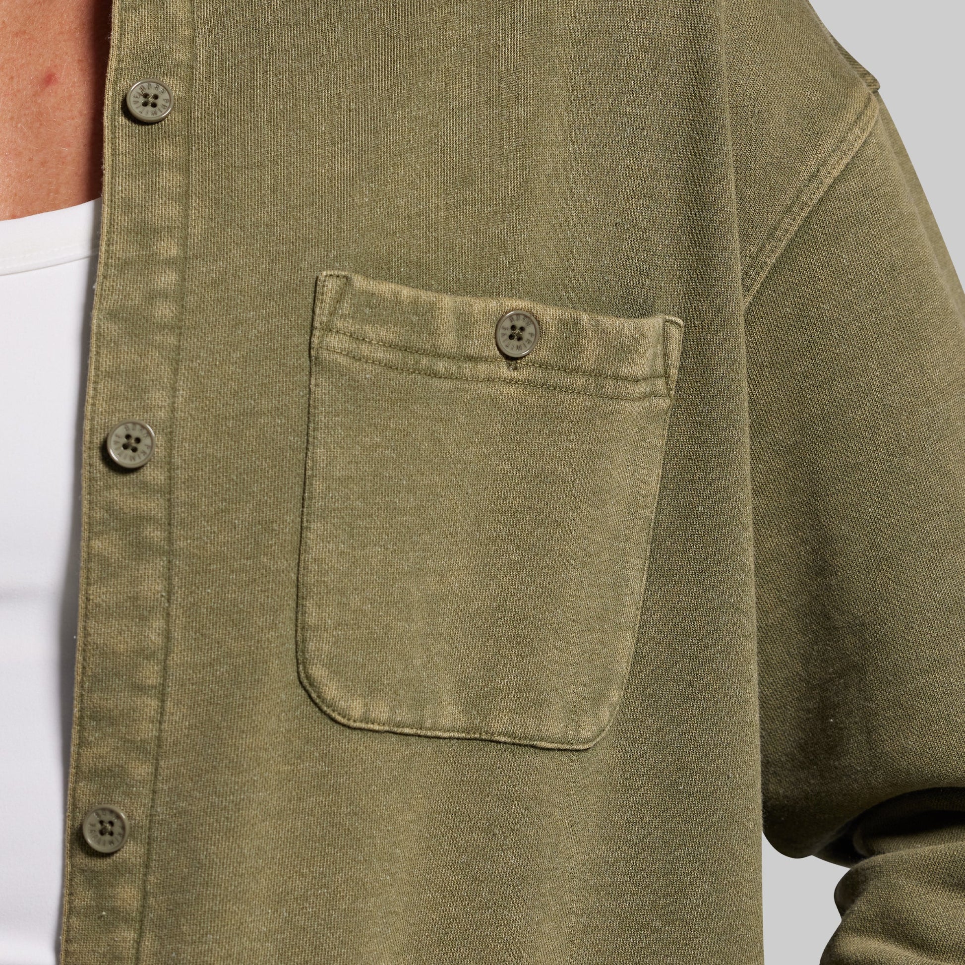 Close-up of a green shirt with a pocket and buttons on a white background
