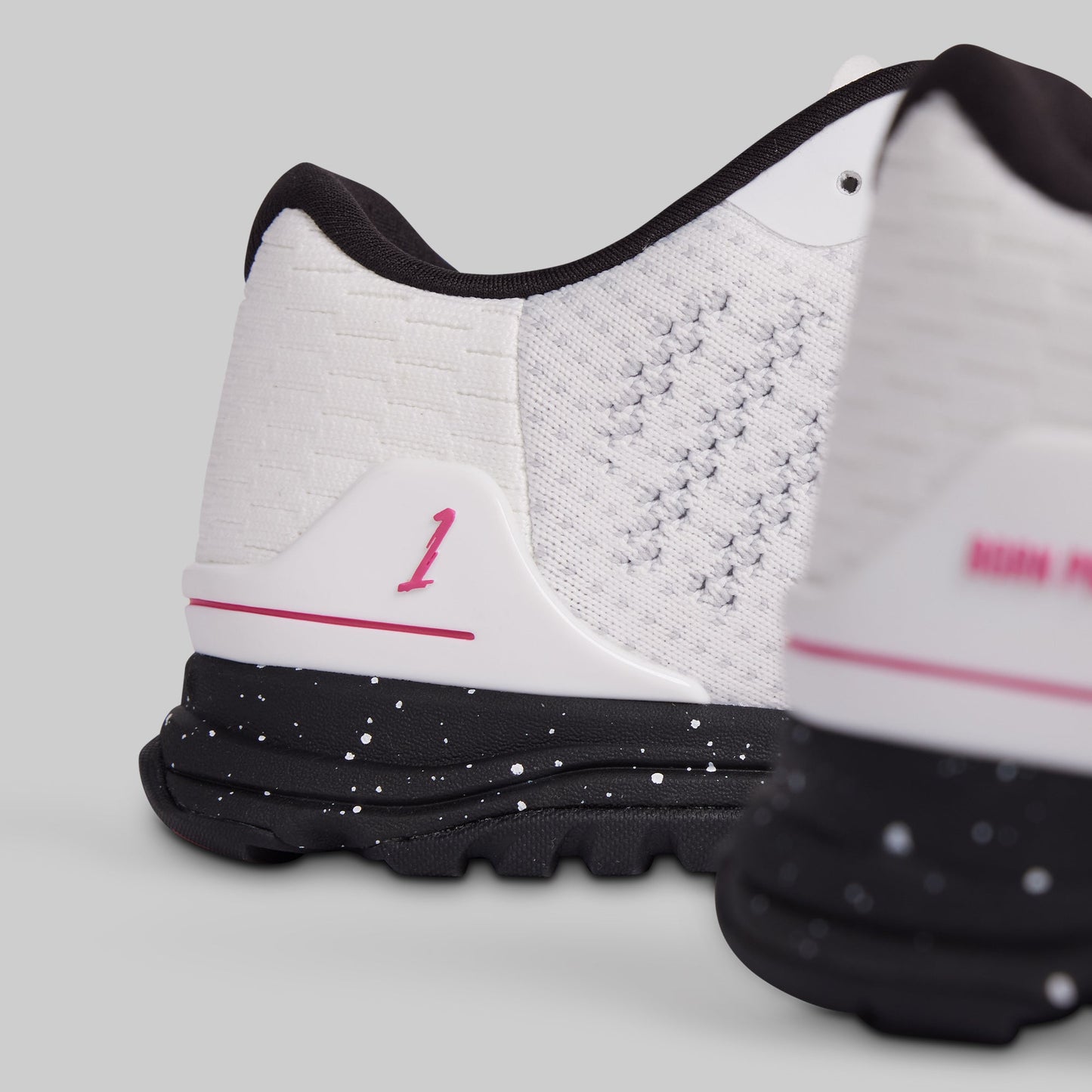 White athletic shoes with black soles and pink accents on a light gray background