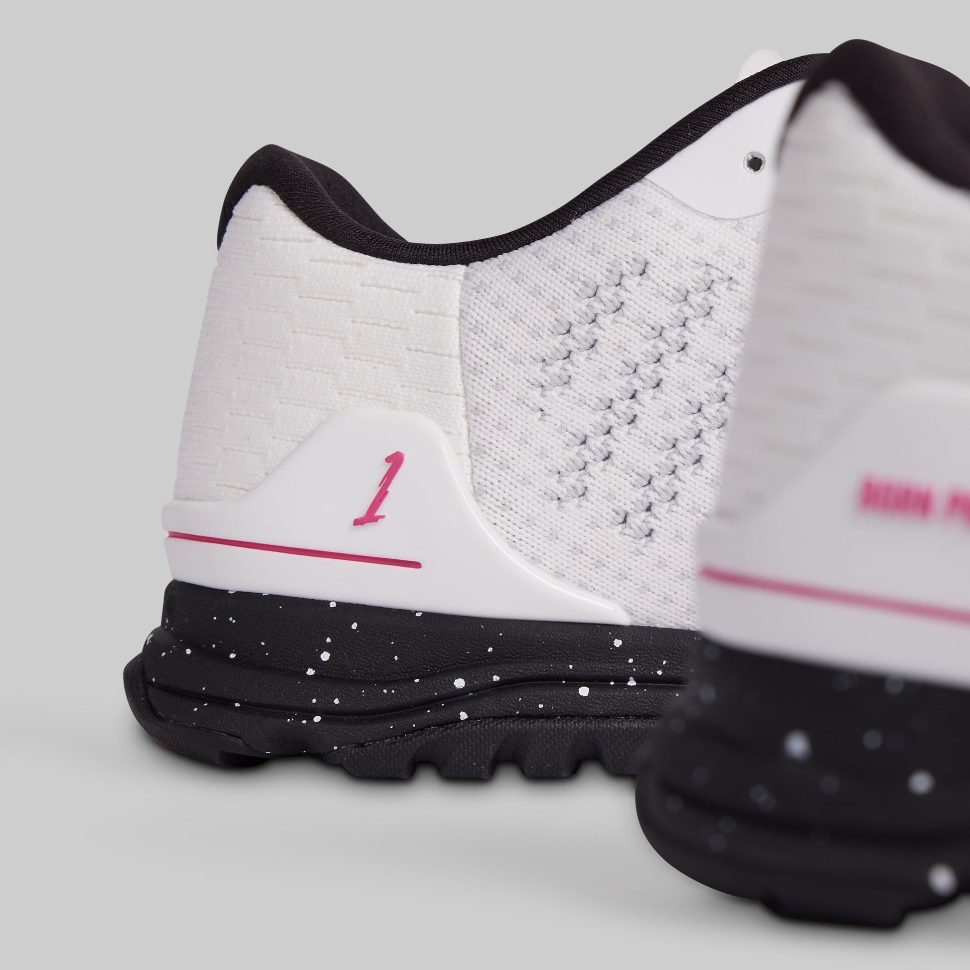 White athletic shoes with black soles and pink accents on a light gray background