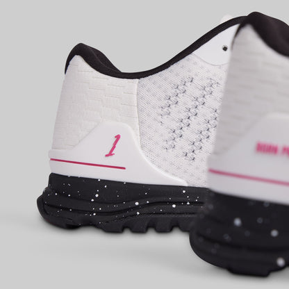 White athletic shoes with black soles and pink accents on a light gray background