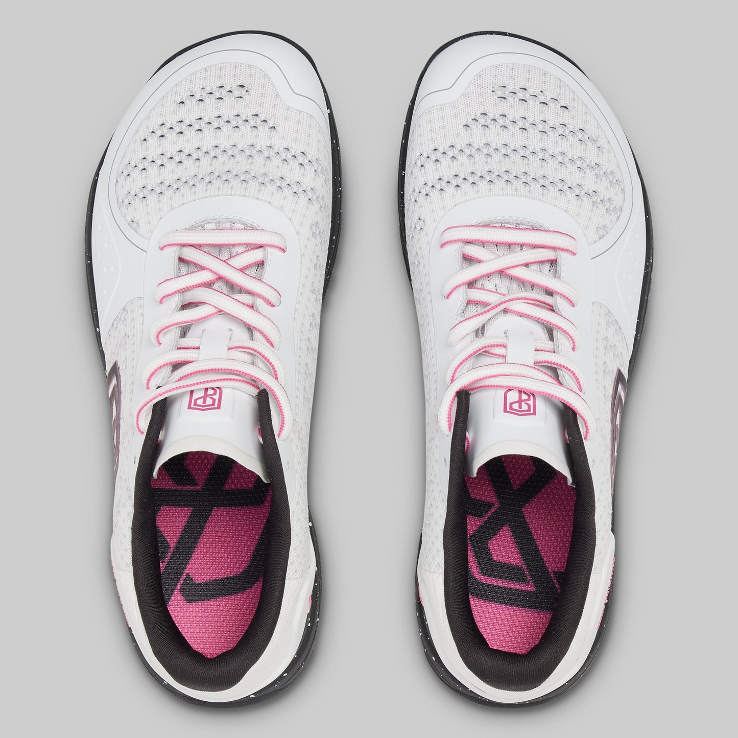 White athletic shoes with pink accents on a gray background