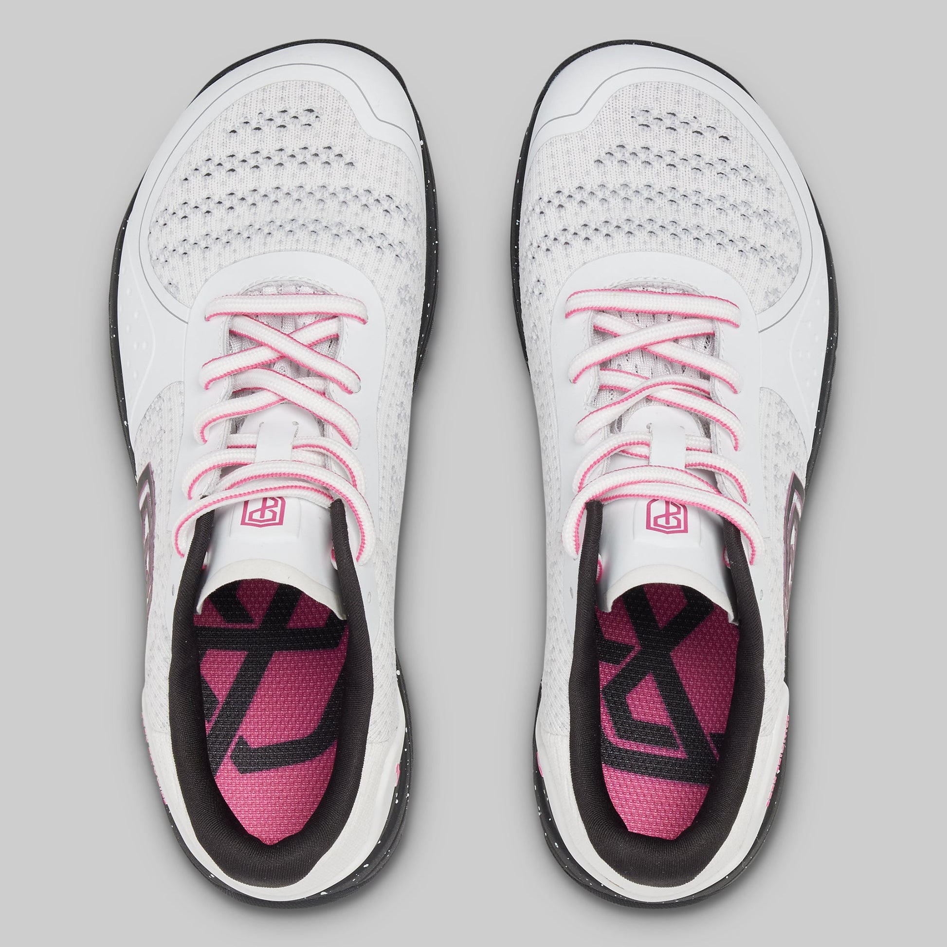White athletic shoes with pink accents on a gray background