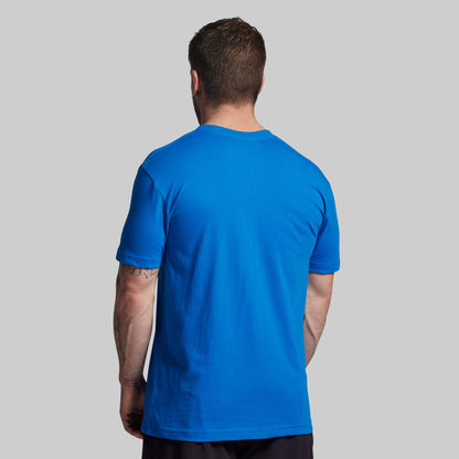 Man wearing a blue t-shirt against a gray background