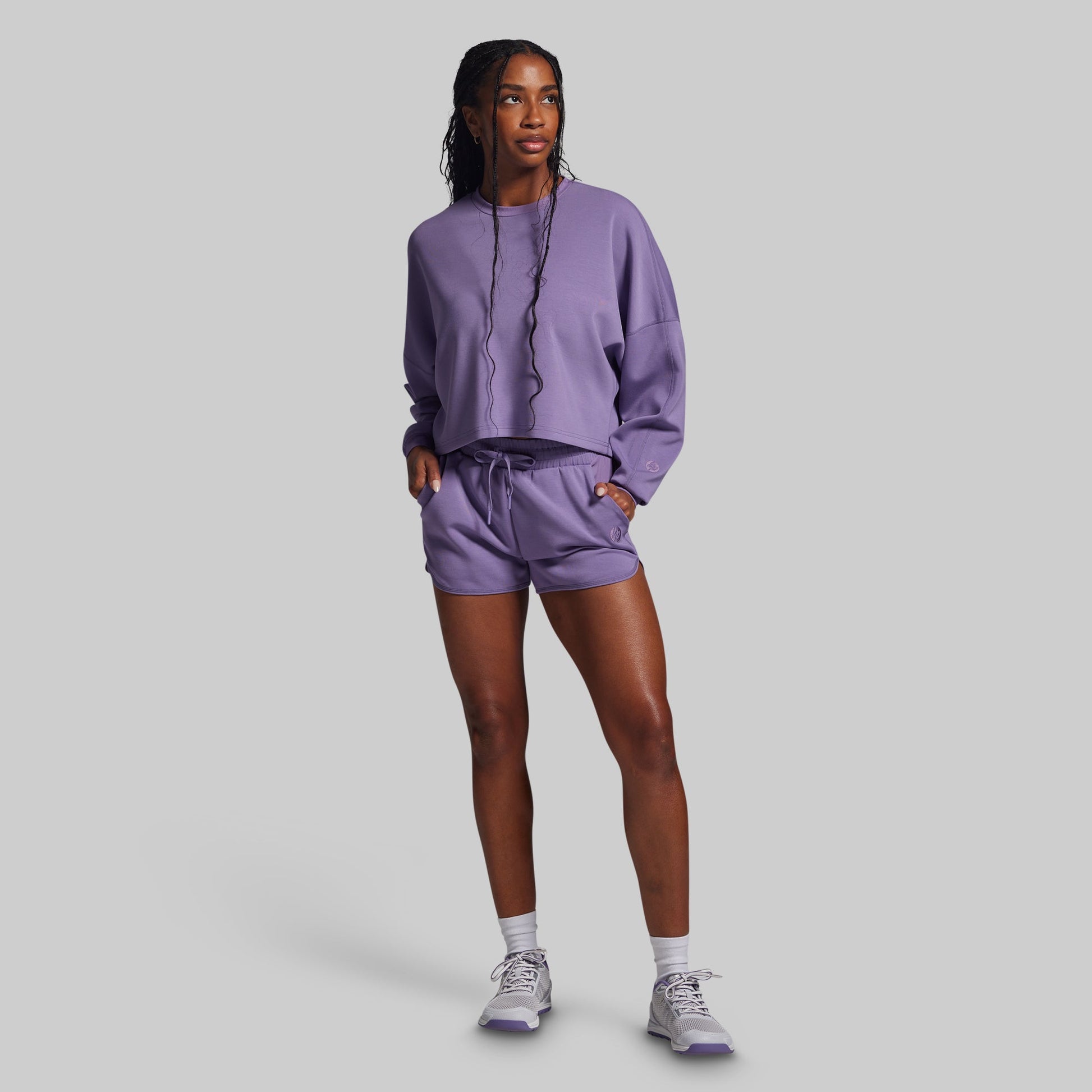 Person wearing a purple sweatshirt and shorts set on a gray background