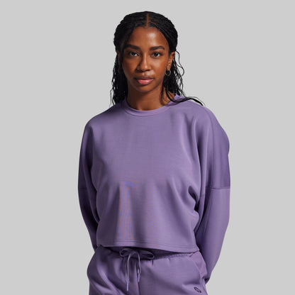 Woman wearing a purple sweatshirt and pants on a gray background