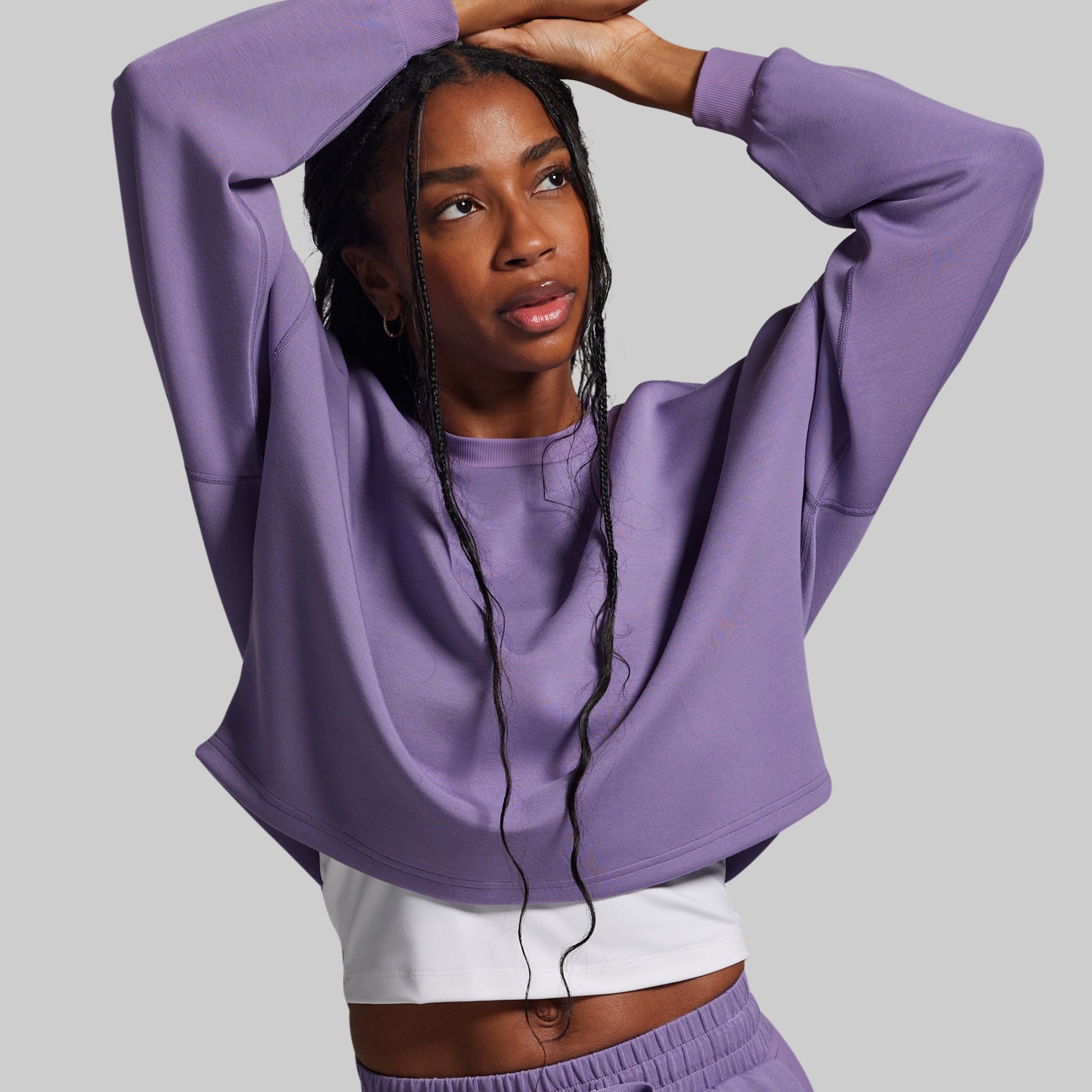 Woman wearing a purple sweatshirt and pants against a gray background