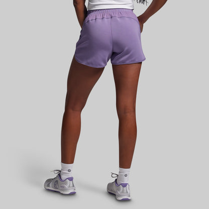 Person wearing purple athletic shorts on a gray background
