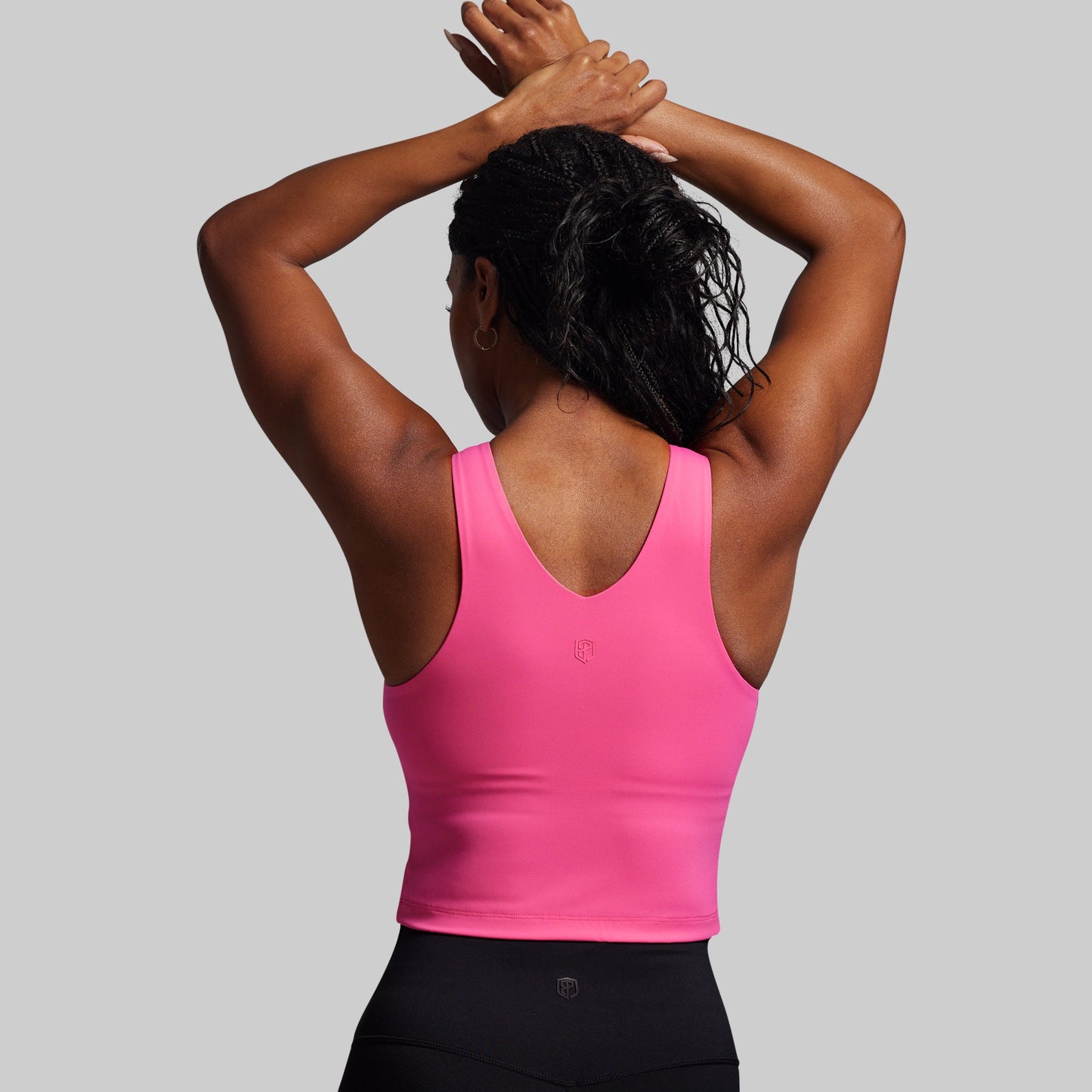 Person wearing a pink tank top with a gray background