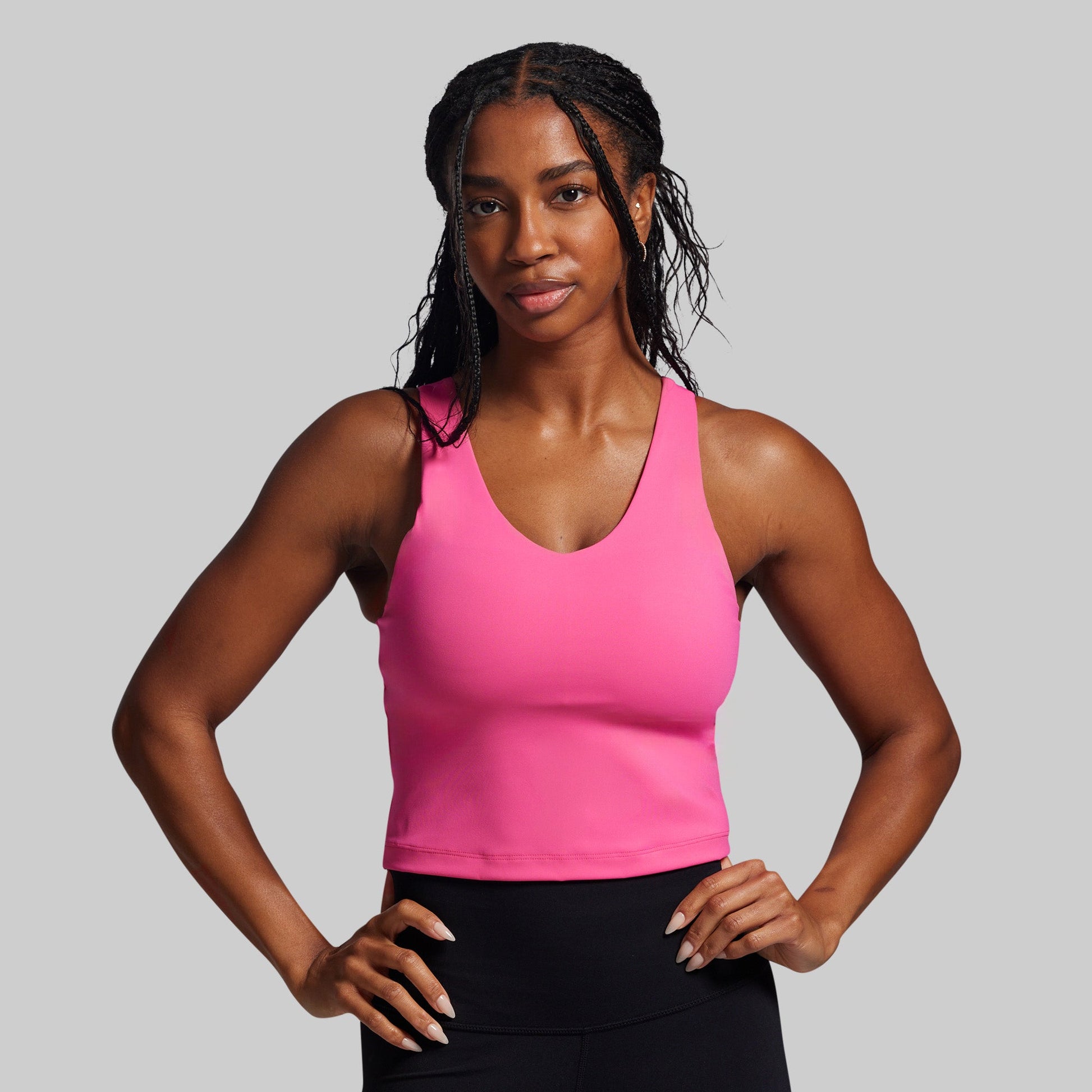 Woman wearing a pink tank top against a gray background