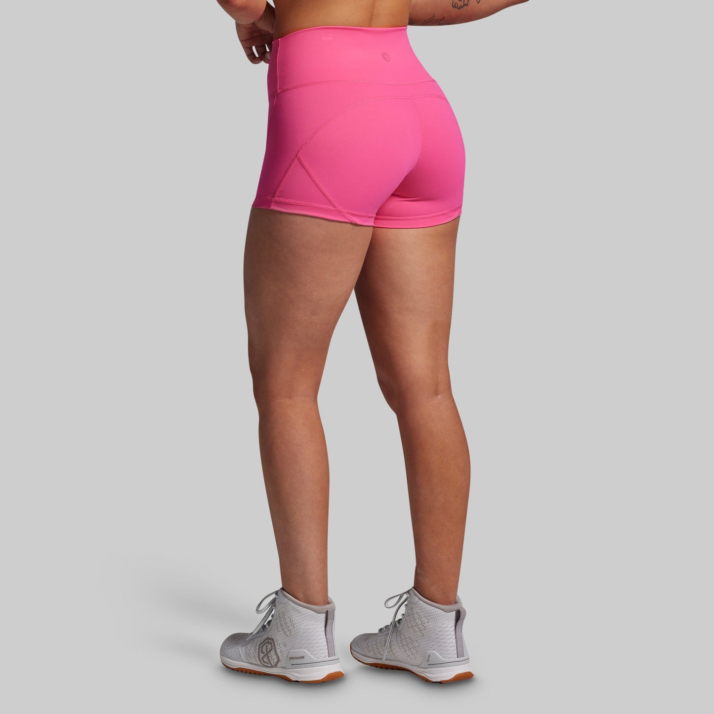 Person wearing bright pink athletic shorts on a gray background