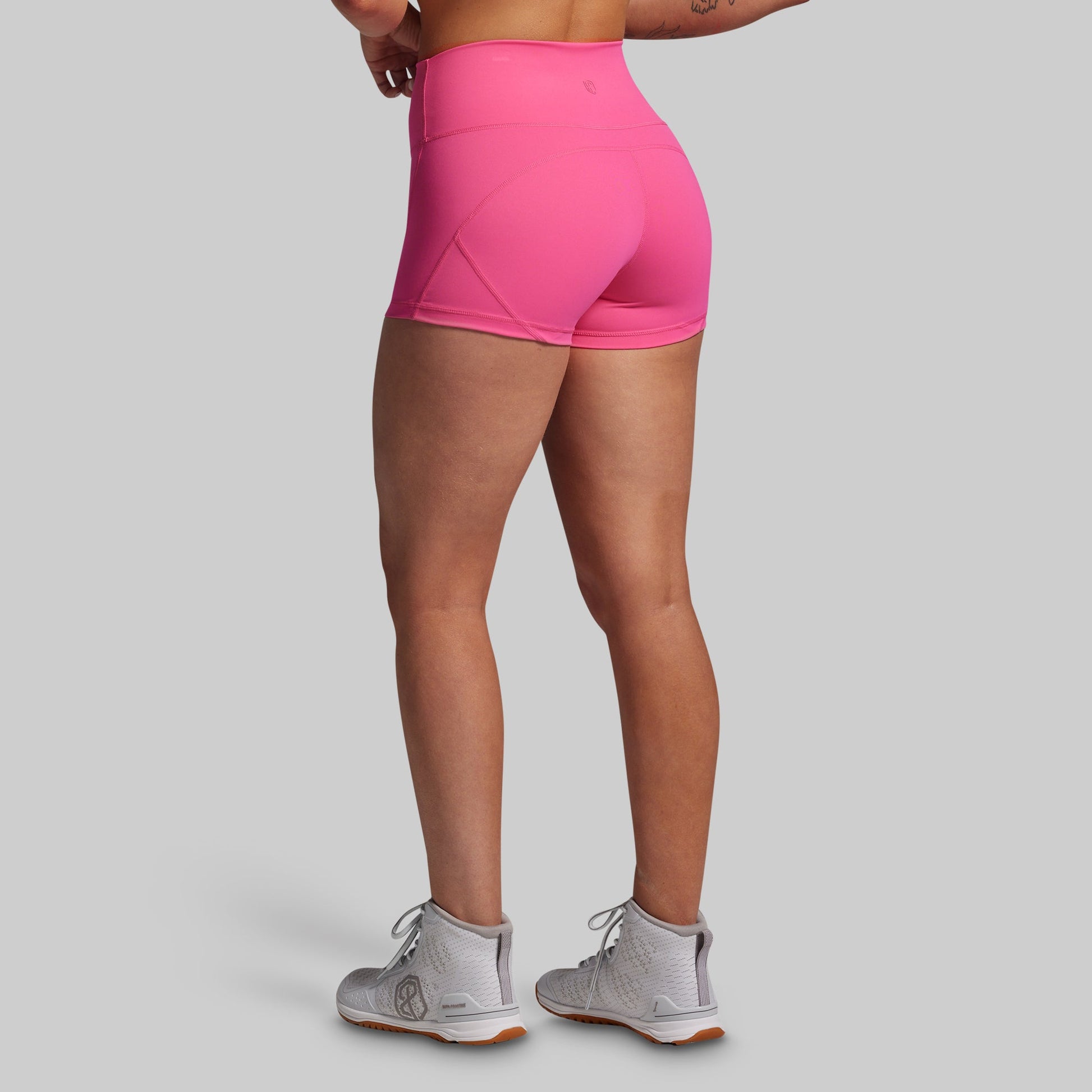 Person wearing bright pink athletic shorts on a gray background