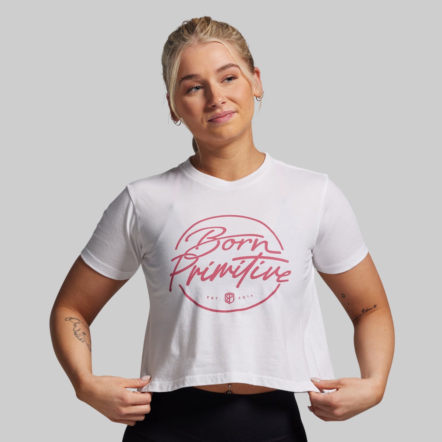 Person wearing a white t-shirt with 'Born Primitive' logo on a gray background