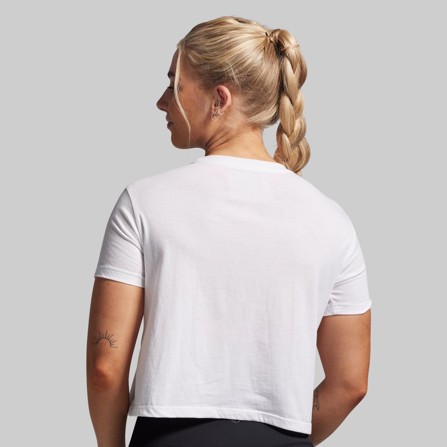 Person wearing a plain white t-shirt on a light gray background