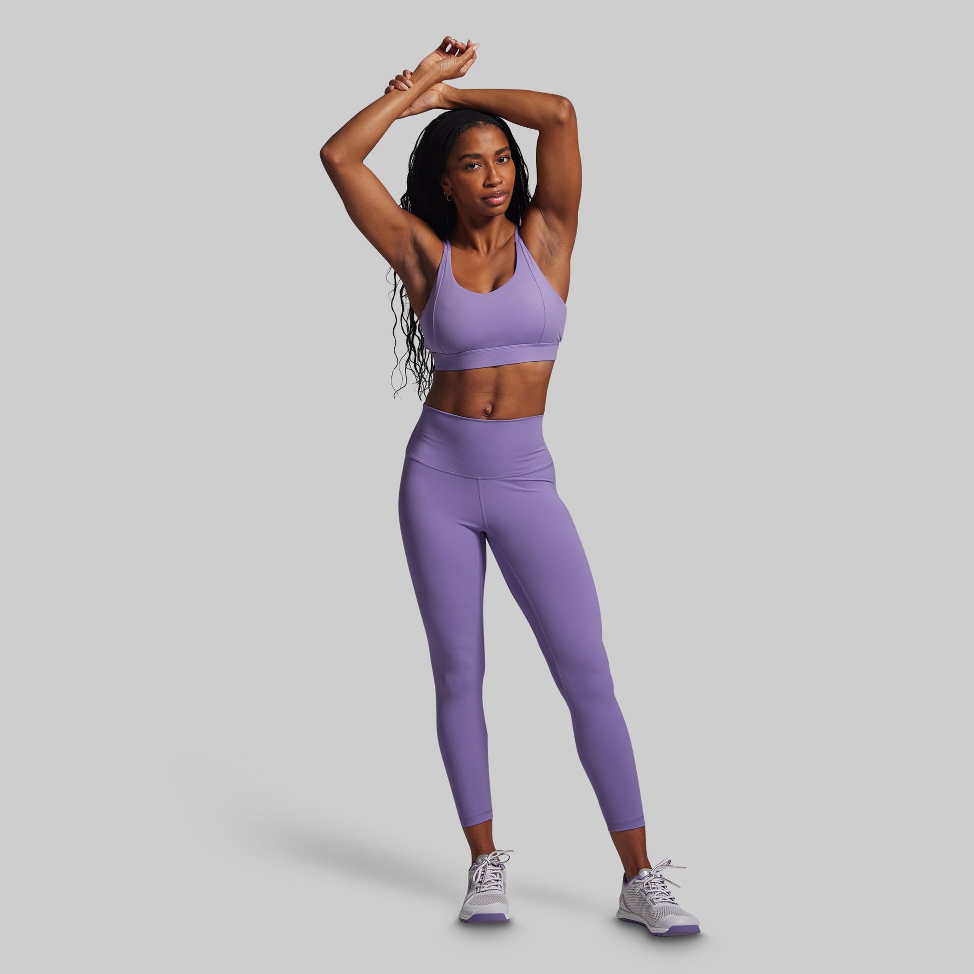 Woman wearing a purple athletic outfit on a gray background