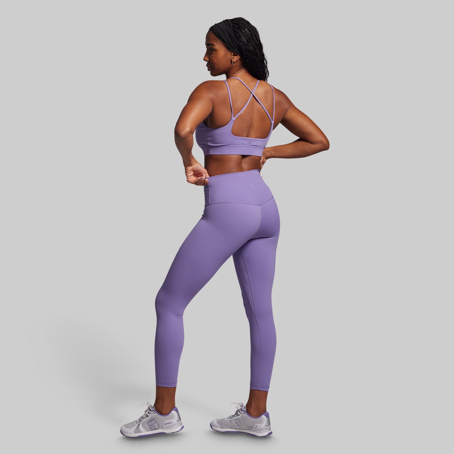 Woman wearing a purple athletic outfit on a gray background