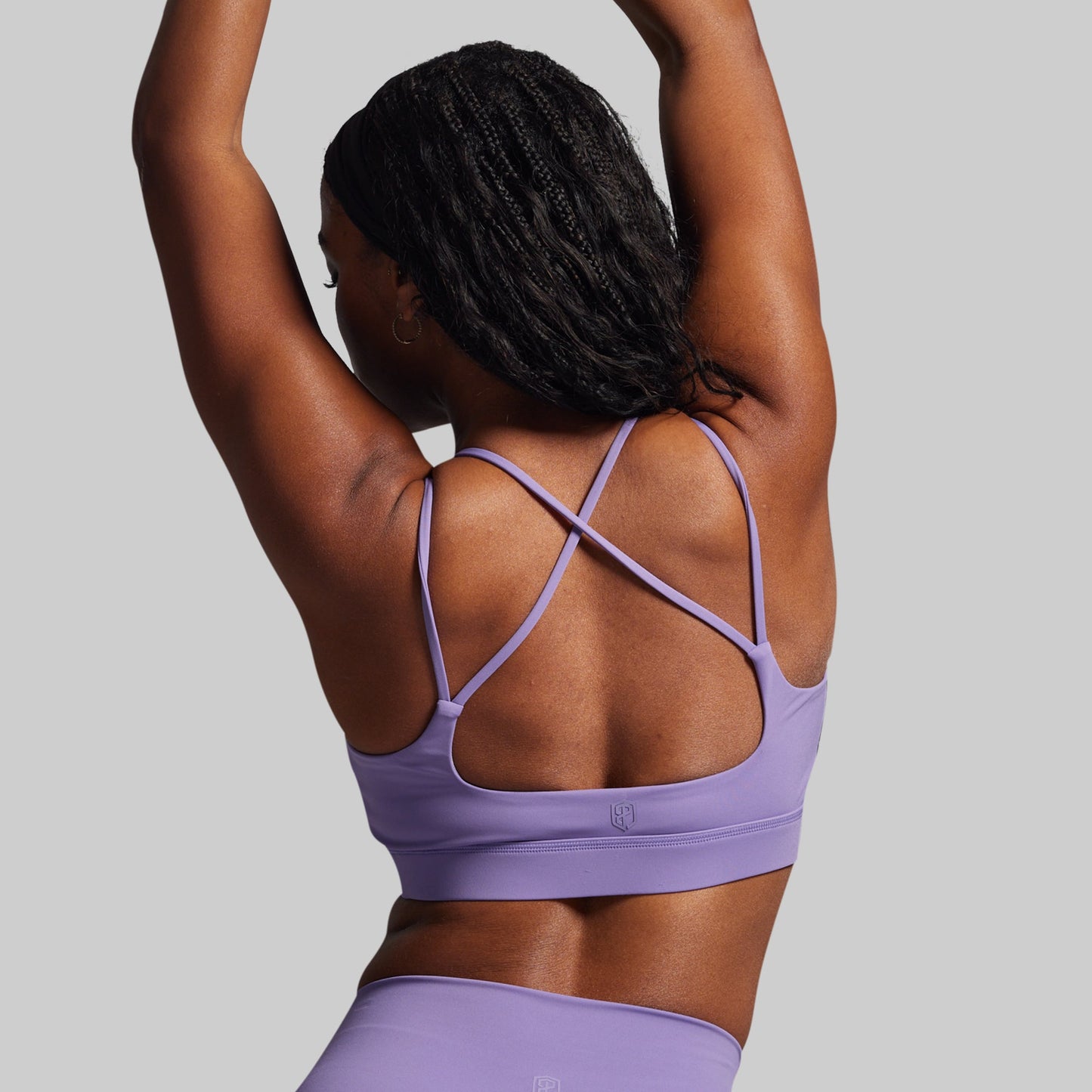 Person wearing a purple sports bra and leggings on a gray background
