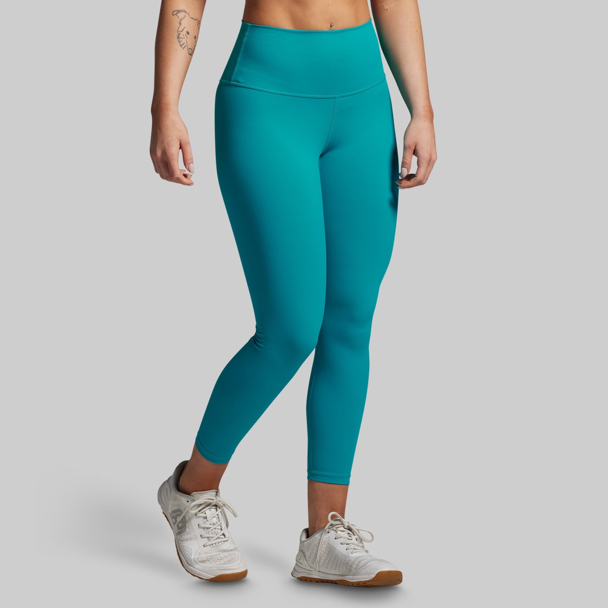 Teal leggings worn by a person on a gray background