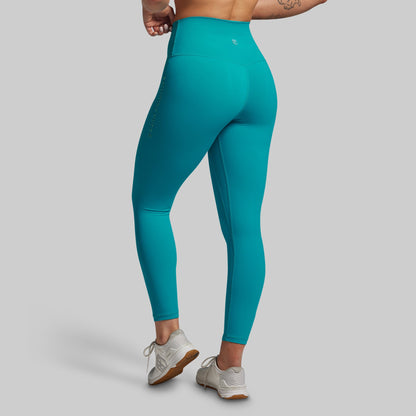Teal leggings worn by a person on a gray background