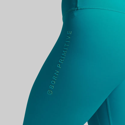 Teal leggings with 'Born Primitive' branding on a gray background
