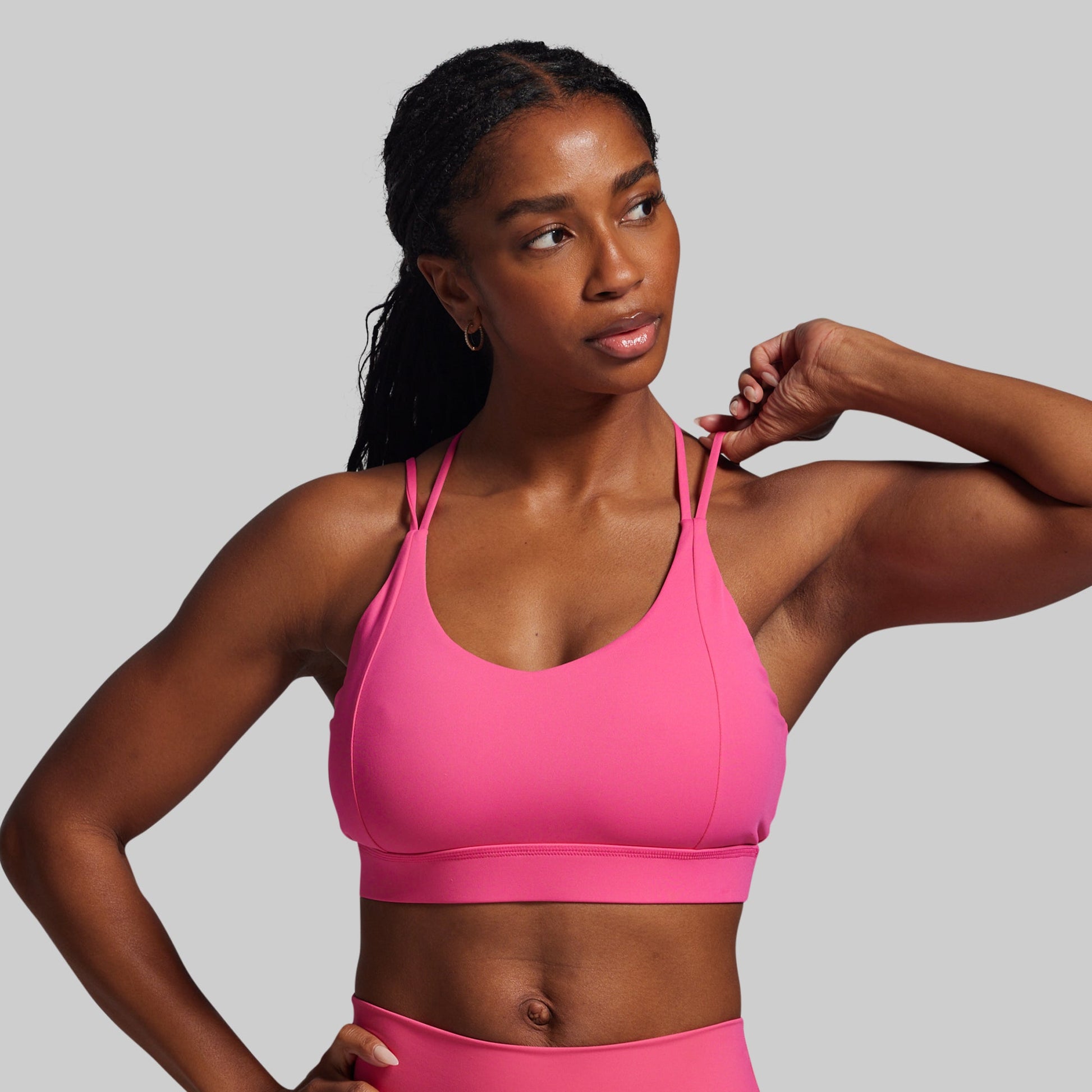 Woman wearing a pink sports bra and leggings against a gray background