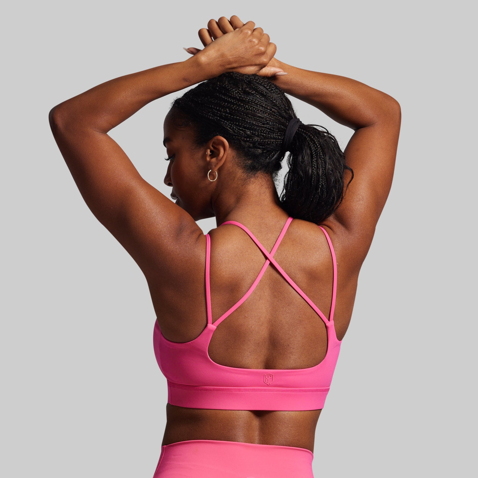 Person wearing a pink sports bra and leggings on a gray background