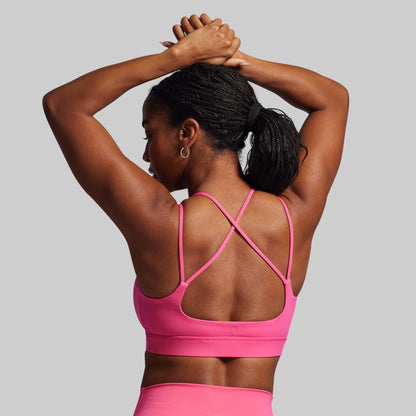 Person wearing a pink sports bra and leggings on a gray background