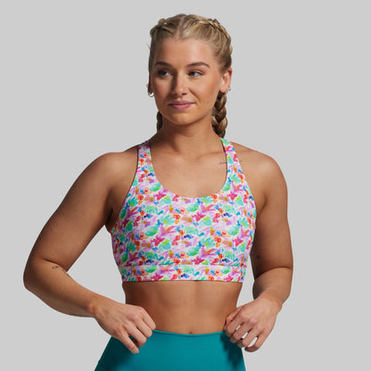 Woman wearing a colorful patterned sports bra and teal shorts on a gray background