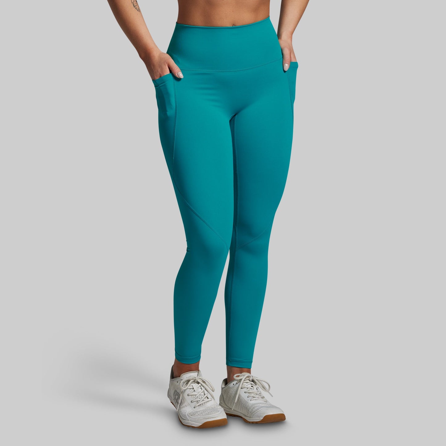 Teal leggings worn by a person on a gray background