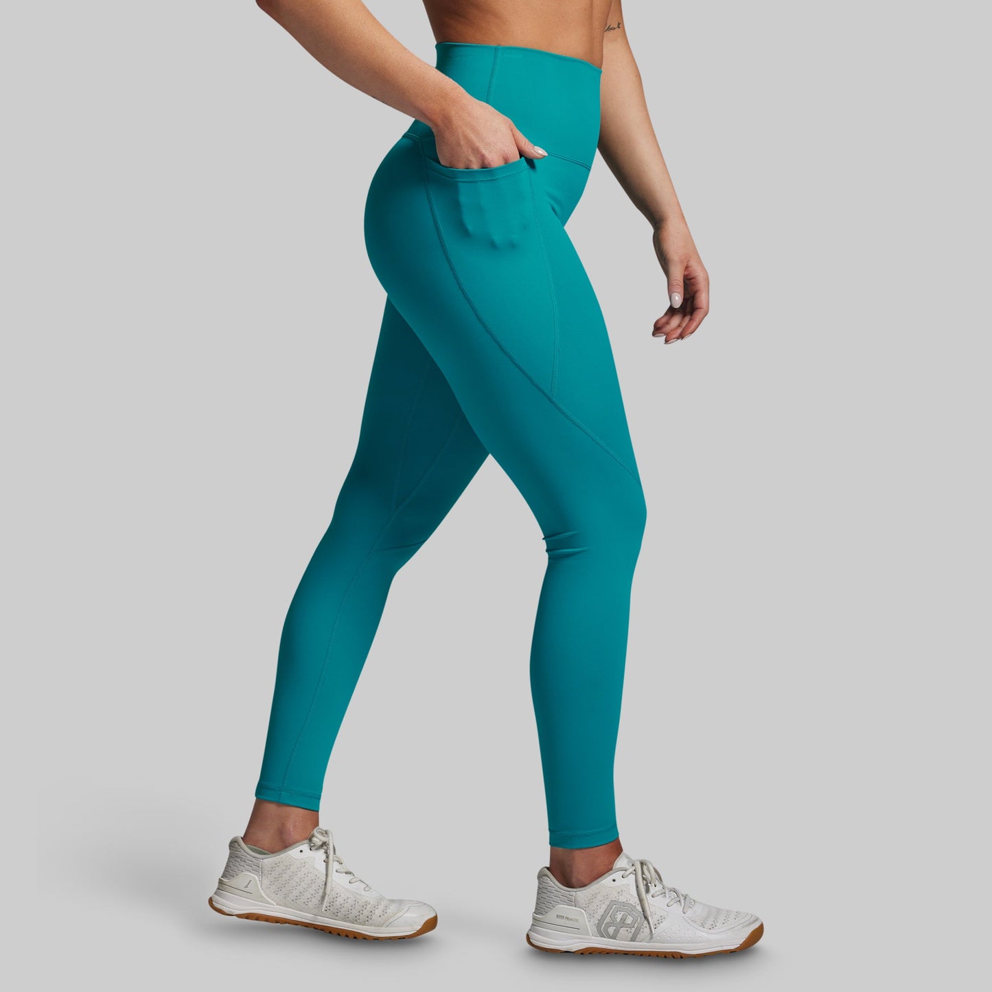 Teal leggings worn by a person on a gray background