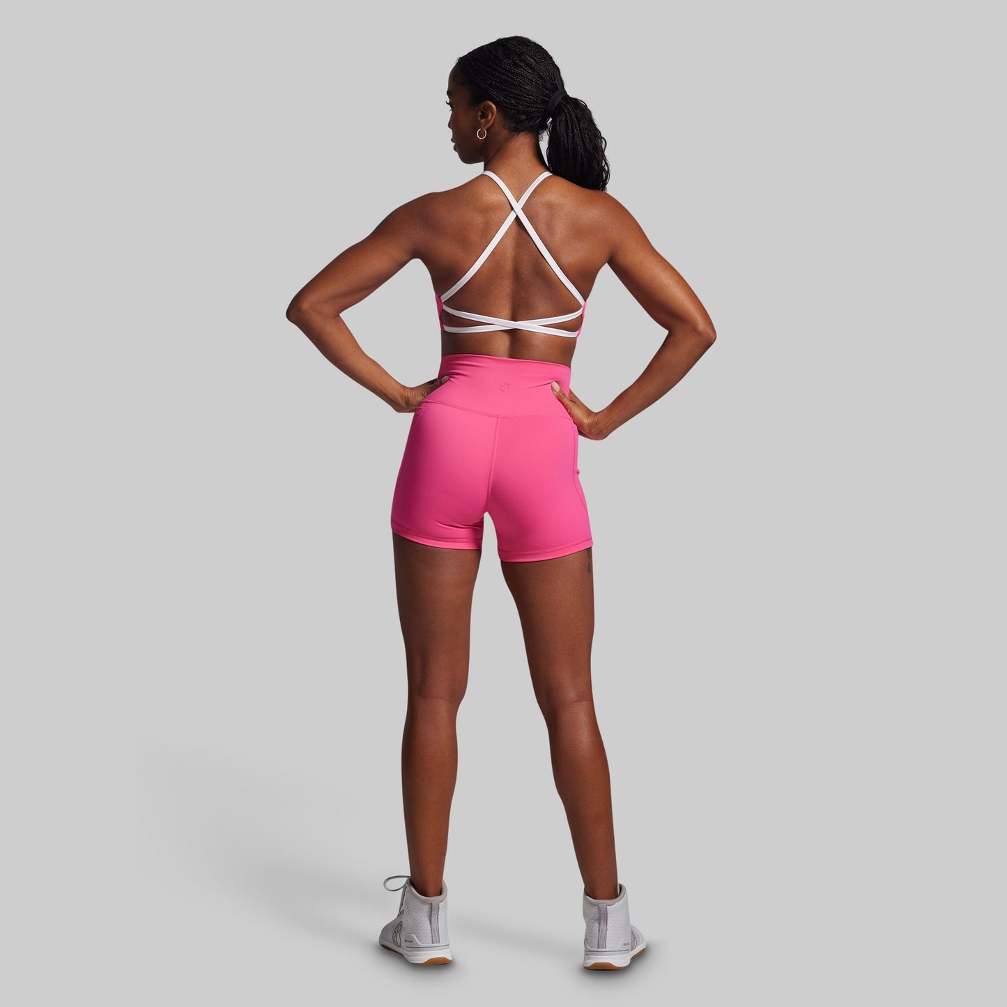 Person wearing a pink athletic outfit with a white sports bra on a gray background