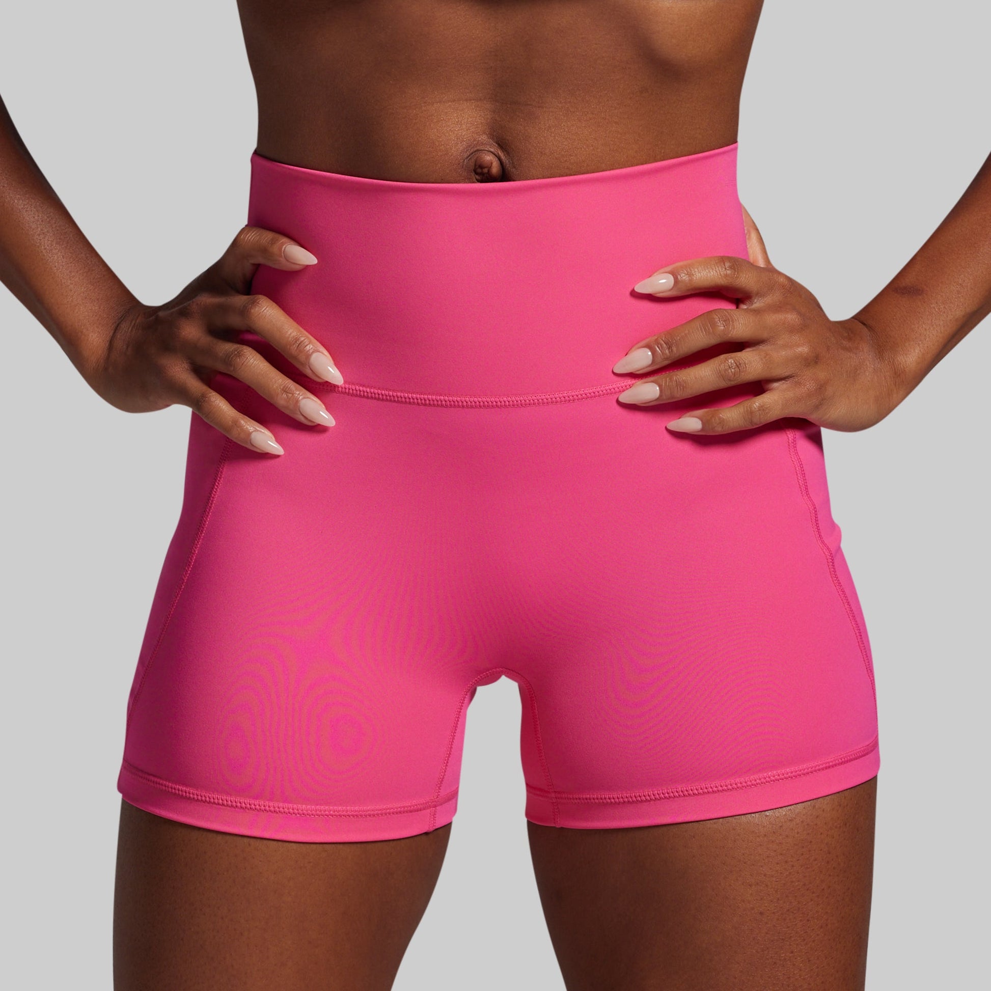 Person wearing bright pink athletic shorts on a gray background