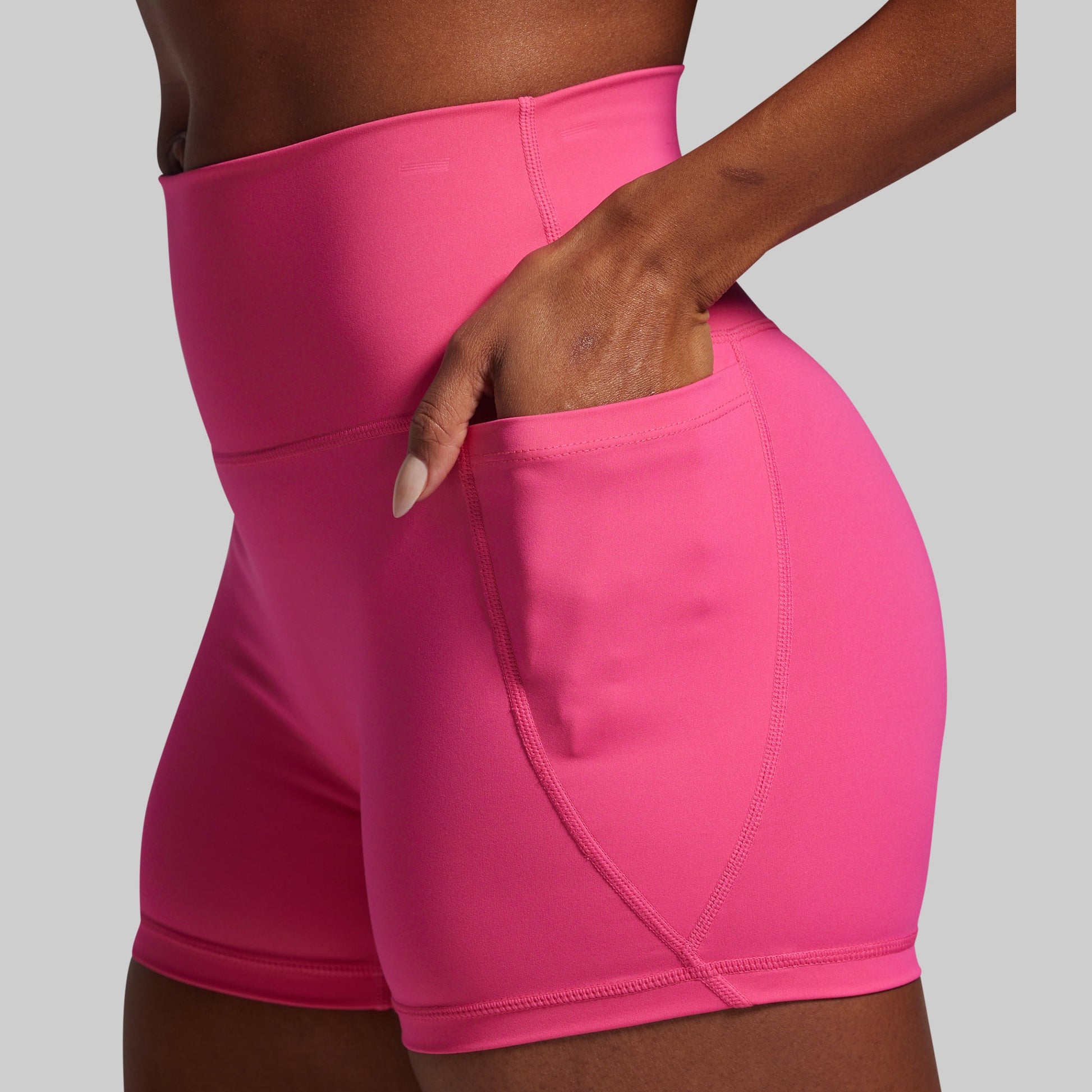 Person wearing bright pink athletic shorts on a gray background