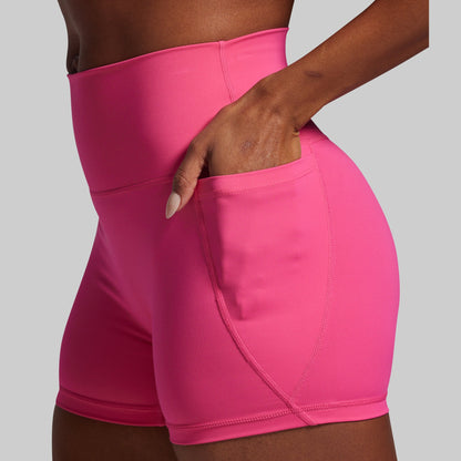 Person wearing bright pink athletic shorts on a gray background