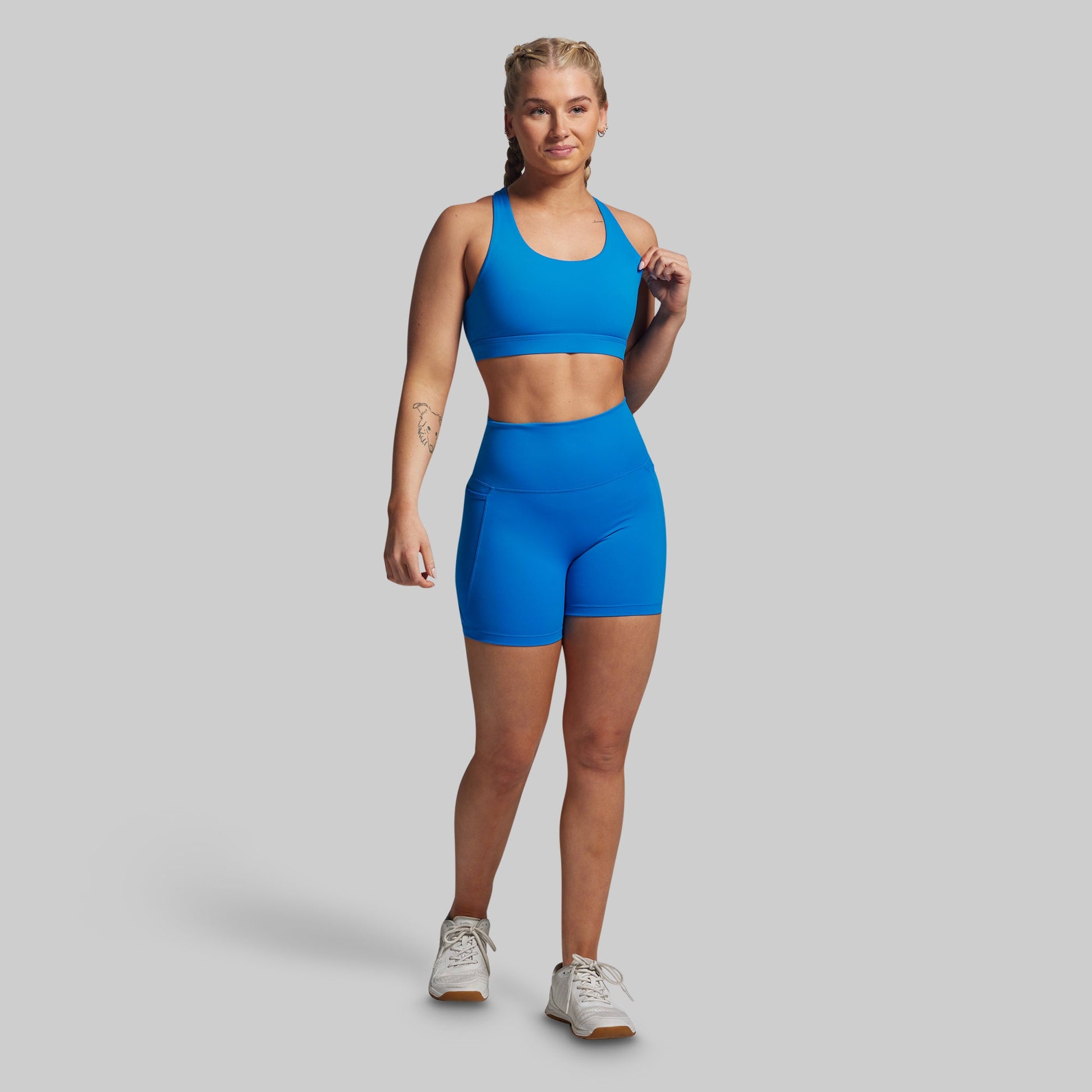 Woman wearing a blue athletic outfit on a gray background